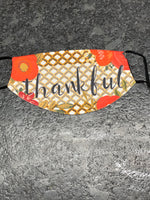 Thankful wording with a nice Fall colored flowers and leaves design Face Cover